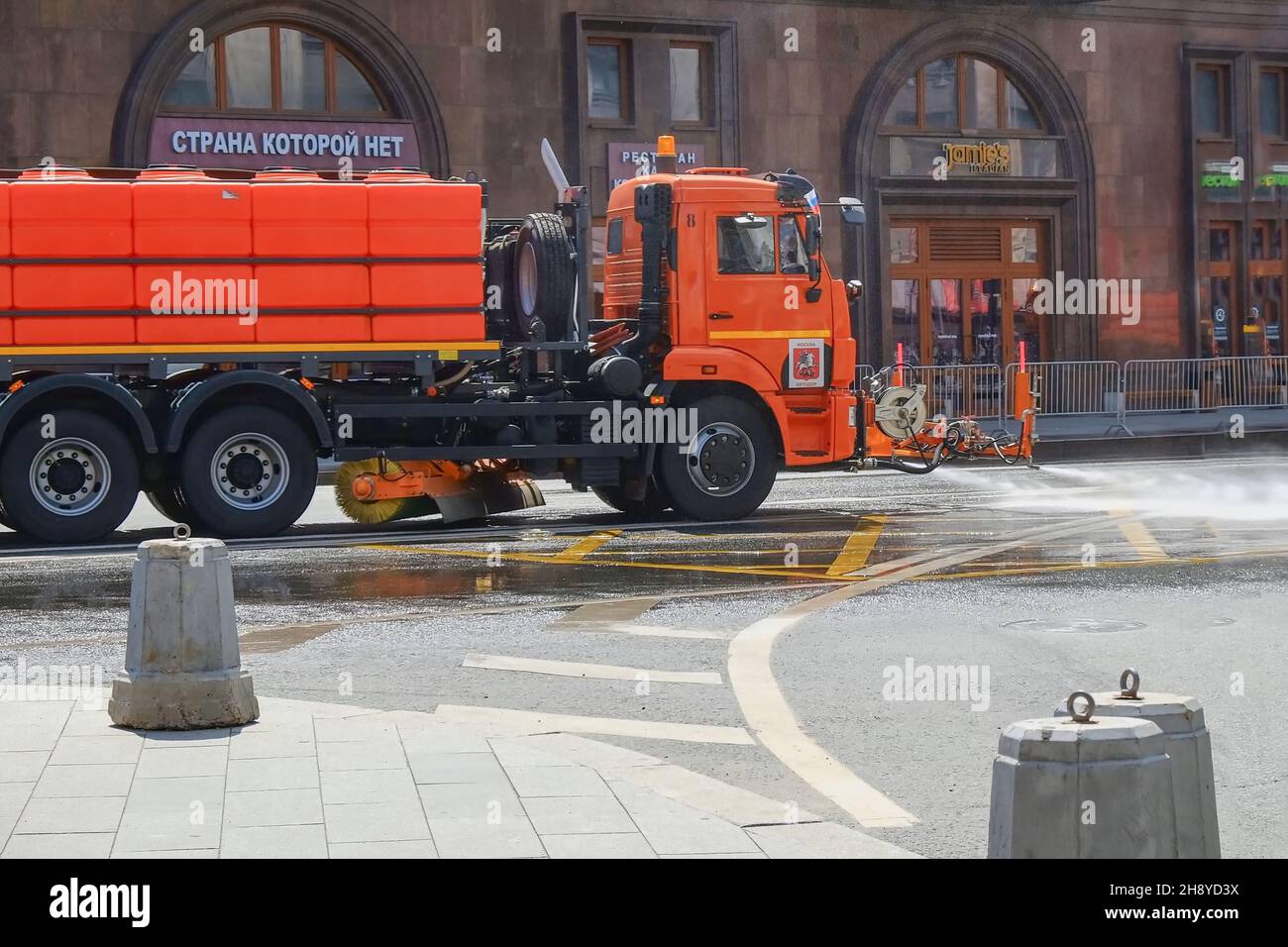Municipal watering machine washes and spray water on asphalt of Moscow city center streets .Urban public utilities  Stock Photo