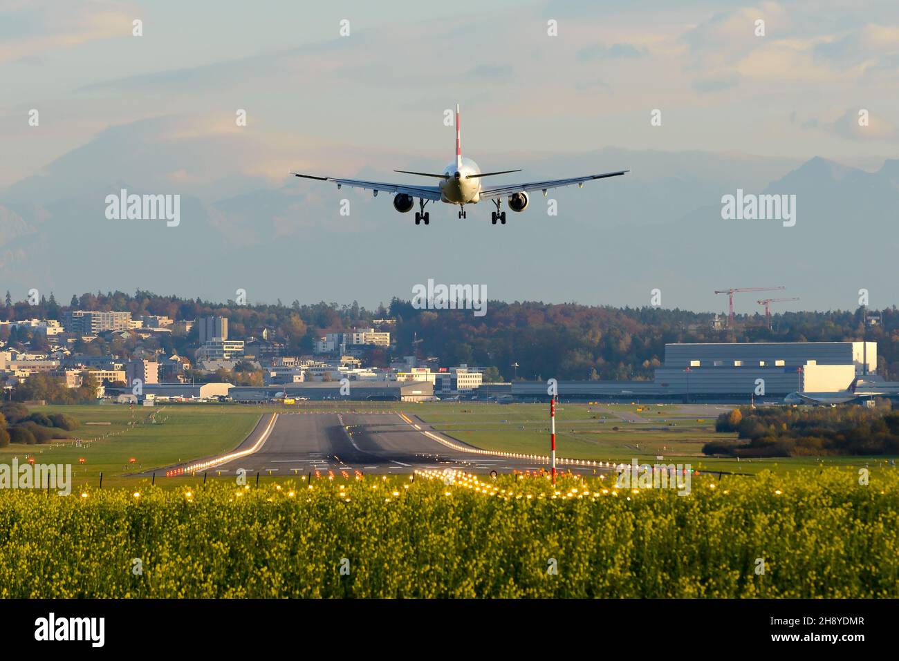 Zurich Airport runway with Swiss Air aircraft landing. Airport located in Kloten, Zurich serving as a hub for air travel. Airplane on final approach. Stock Photo