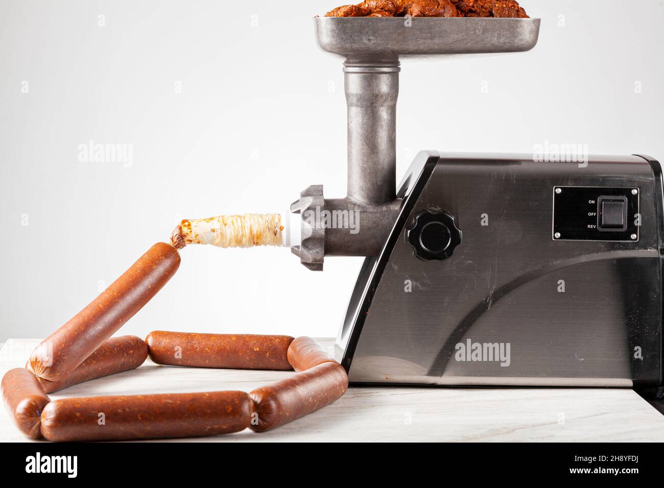Close up isolated image of homemade sucuk or Sausage that is being stuffed into casing using electrical stuffer device. Stock Photo