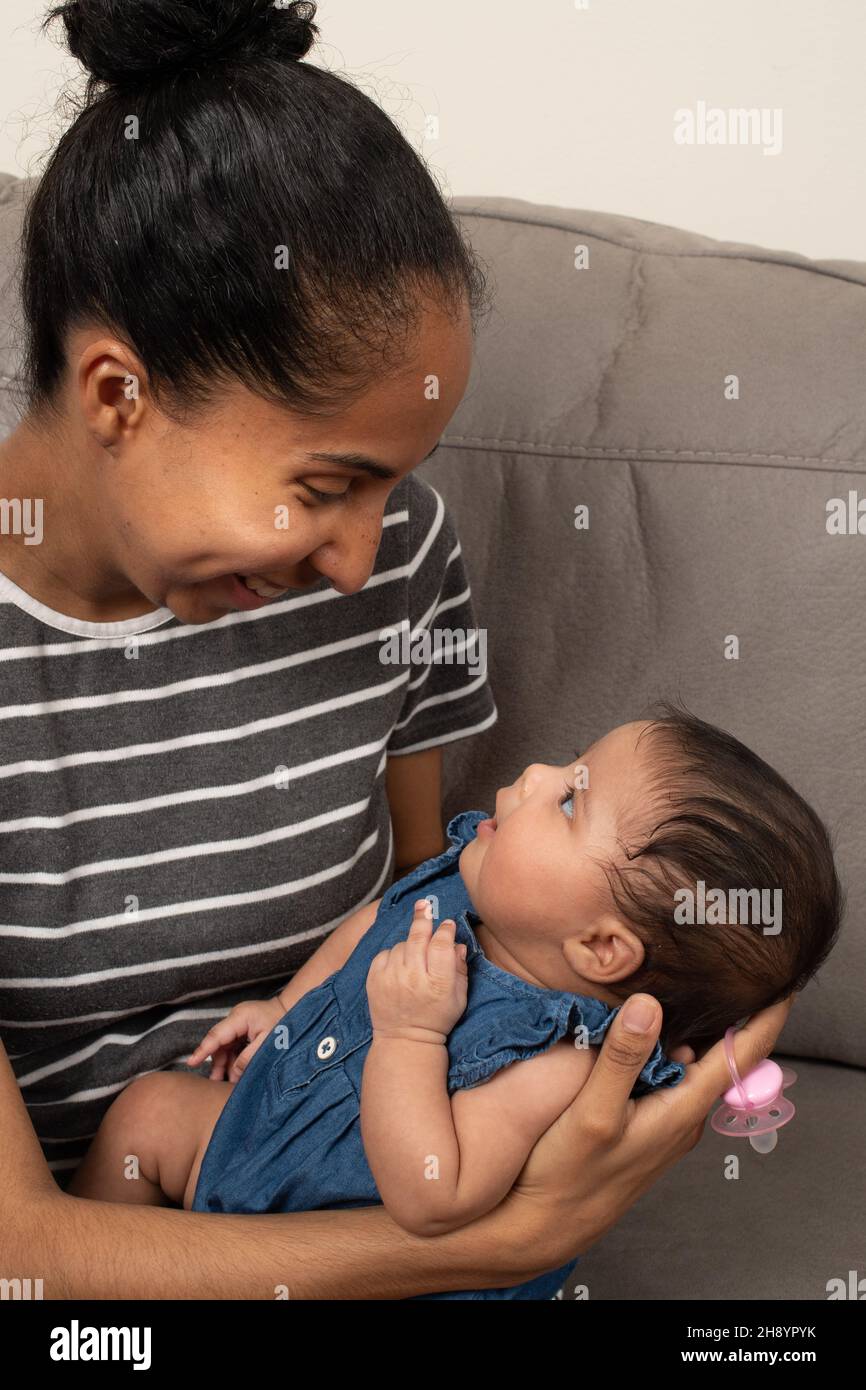 2 month old baby girl held by mother, interacting with her Stock Photo