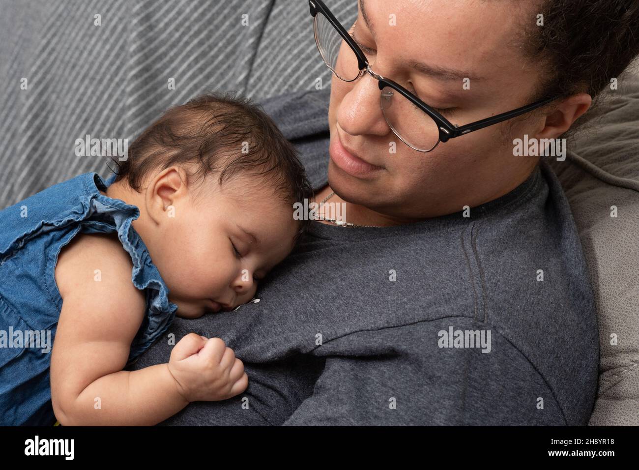 2 month old baby girl (premature) sleeping on chest of caregiver Stock Photo