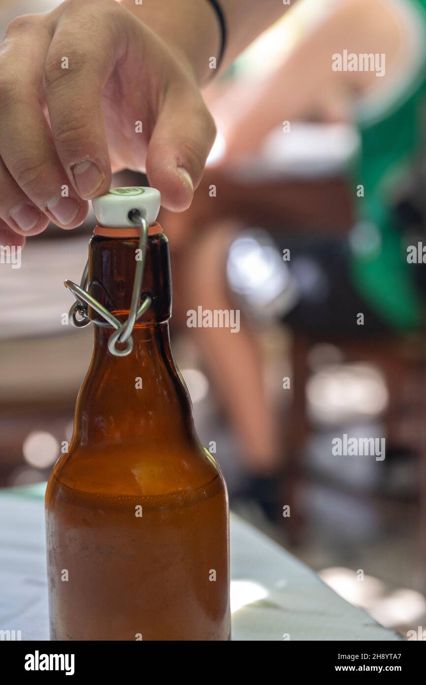 man opening the bottle cap on a brown bottle of ginger beer Stock Photo