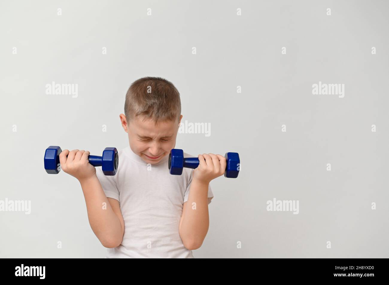 a boy 8-10 years old with dumbbells on a white background. mock up Stock Photo