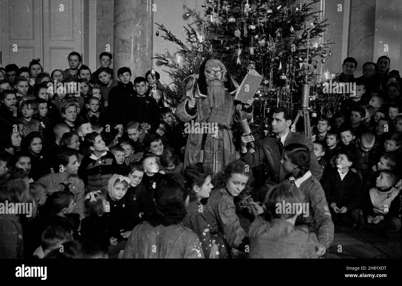 Warszawa, 1946-12. Choinka dla najbiedniejszych dzieci zorganizowana przez premiera Edwarda Osóbkê-Morawskiego w Sali Kolumnowej Pa³acu Namiestnikowskiego, siedzibie Rady Ministrów przy Krakowskim Przedmieœciu. Dzieci otrzyma³y paczki z prezentami. Z mikrofonem sprawozdawca radiowy redaktor Tadeusz Pyszkowski. rd PAP/Jerzy Baranowski Dok³adny dzieñ wydarzenia nieustalony. Warszaw, Dec. 1946. Christmas party for the poorest children organized by Prime Minister Edward Osobka-Morawski at the Kolumnowa Hall of the Namiestnikowski Palace, the seat of the Council of Ministers on Krakowskie Pr Stock Photo