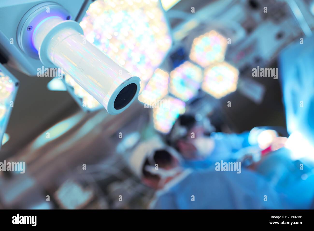 Blurred surgeons in the operating room and surgical lamp close-up. Stock Photo