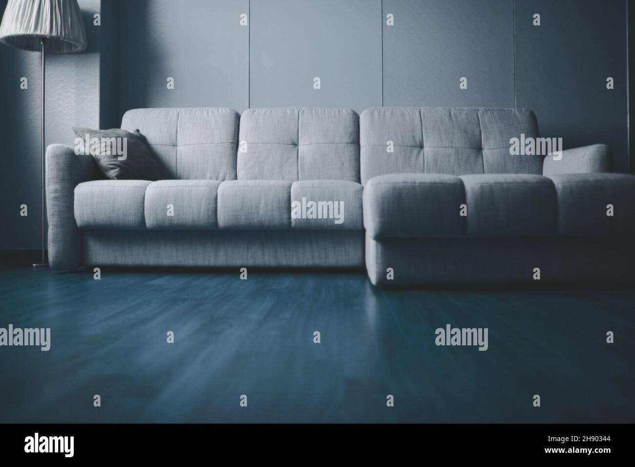 Apartment interior with couch and floor lamp along the wall. Stock Photo
