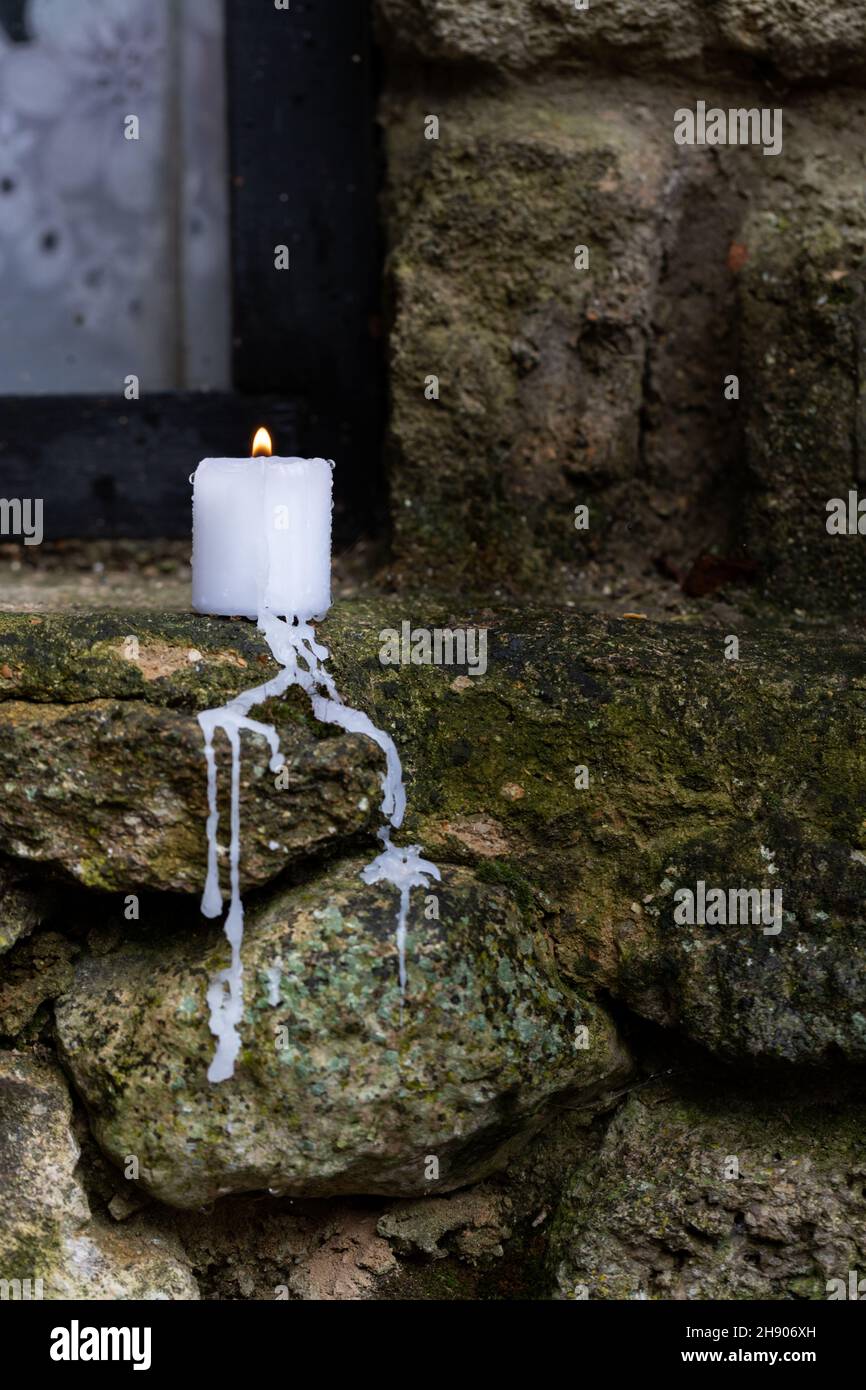 A candle burns on the windowsill of an old limestone house by the