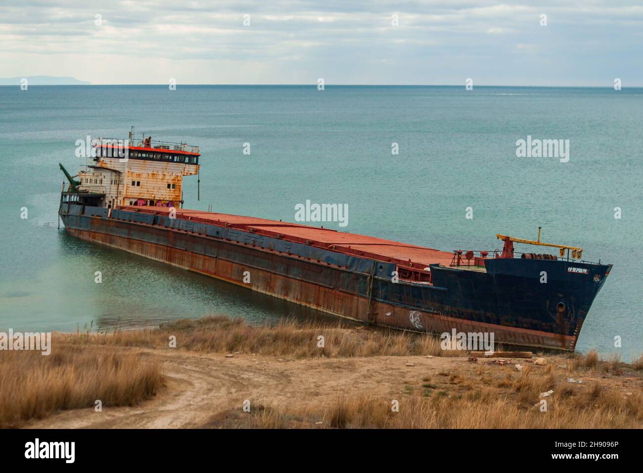 Surov-a big old ship wrecked on the Russian coast and abandoned on the beach. Traces of oil products can be seen on the surface of the water Stock Photo