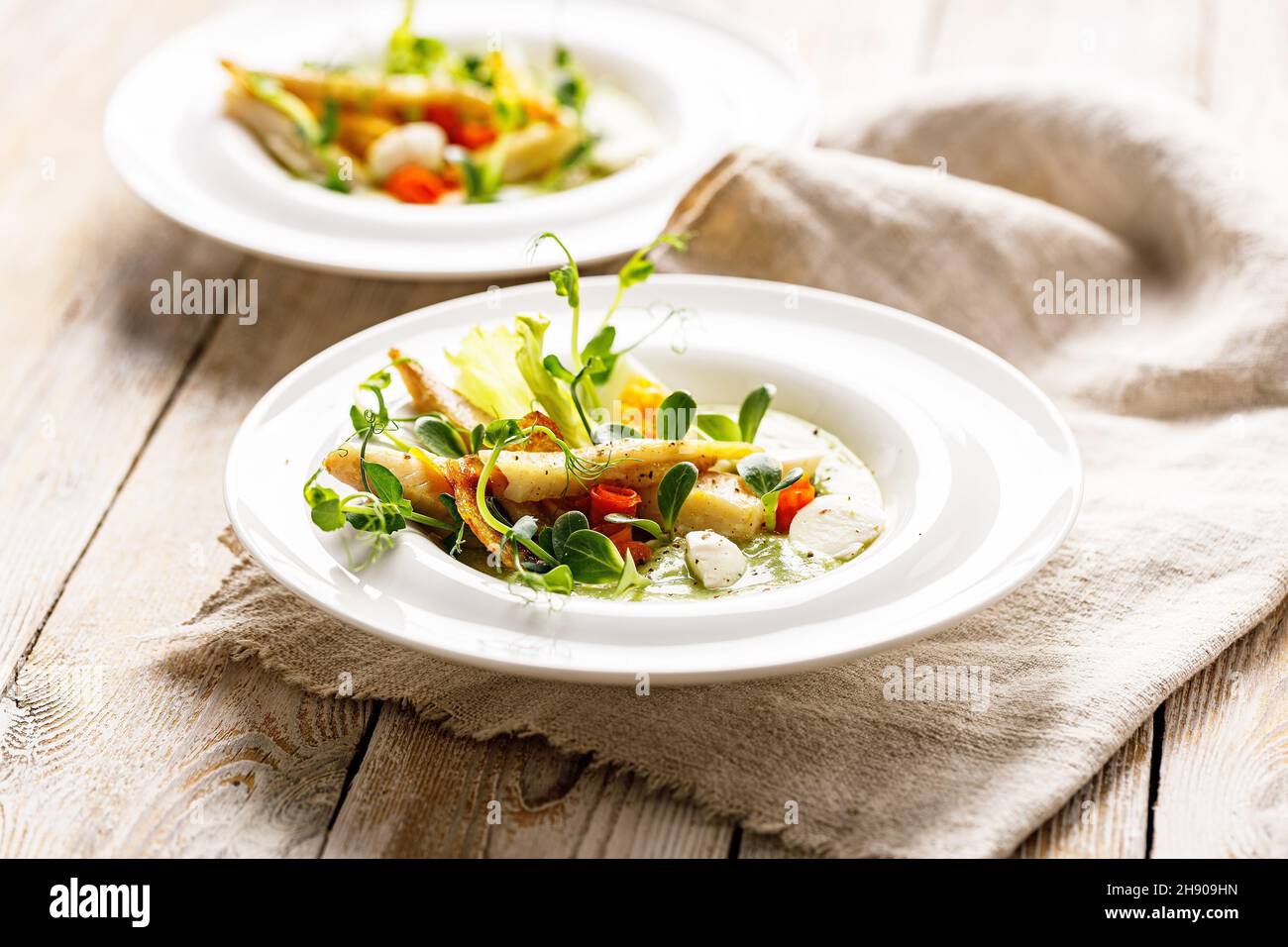Gourmet fish salad. Pangasius dori fillet, vegetables, avocado pate, mozzarella and fresh herbs. Restaurant serving. Chef's dish. Healthy and tasty fo Stock Photo