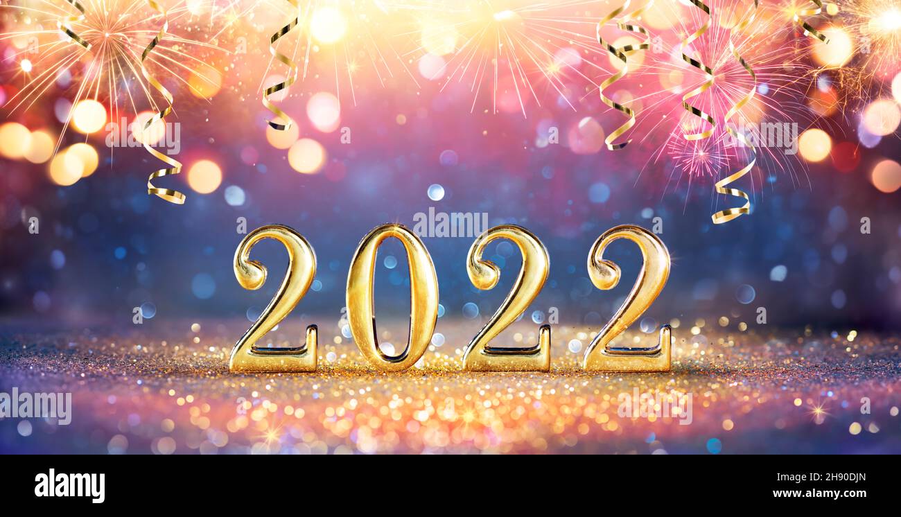 2022 New Year Celebration - Golden Numbers On Glitter With Fireworks And Abstract Defocused Lights Stock Photo
