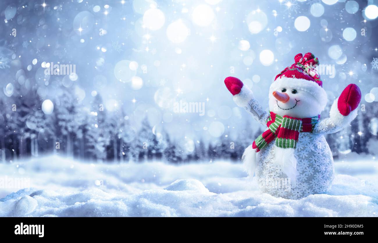 Snowman On Snow In Forest With Snowfall In Defocused Landscape Stock Photo
