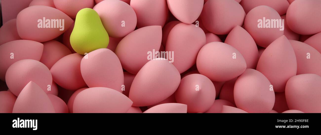 beauty background a bunch of pink gentle sponges and one contrast green conflict for makeup banner Stock Photo