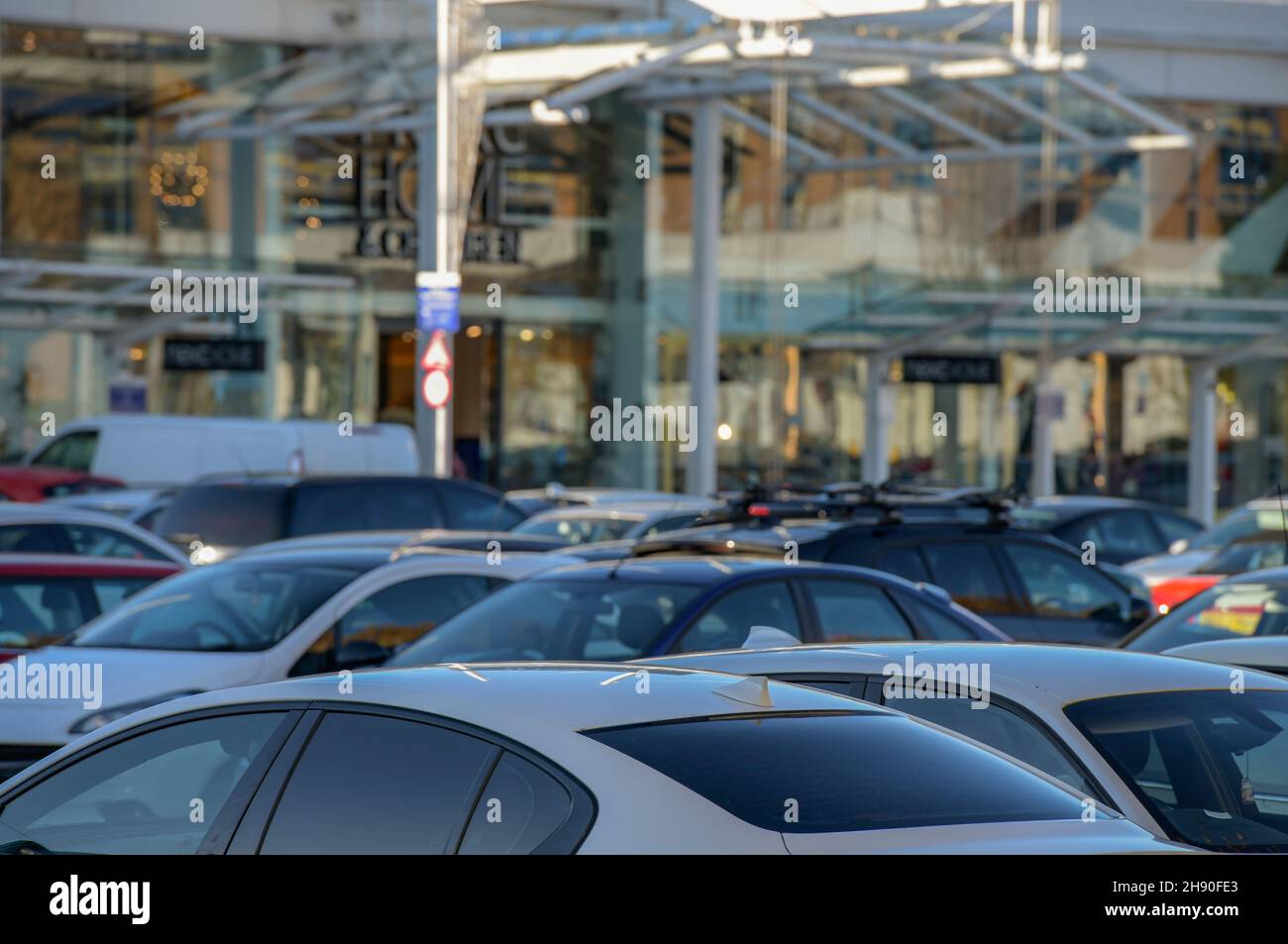 full car park at an out of town shopping centre, modern retail park with on-site parking for customers, large car park outside of modern stores shops. Stock Photo