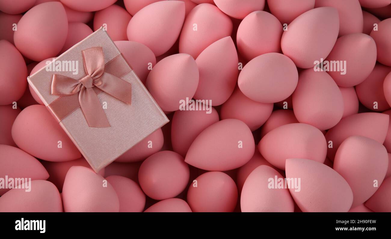 beauty background a bunch of pink gentle makeup sponges and a pink gift banner Stock Photo