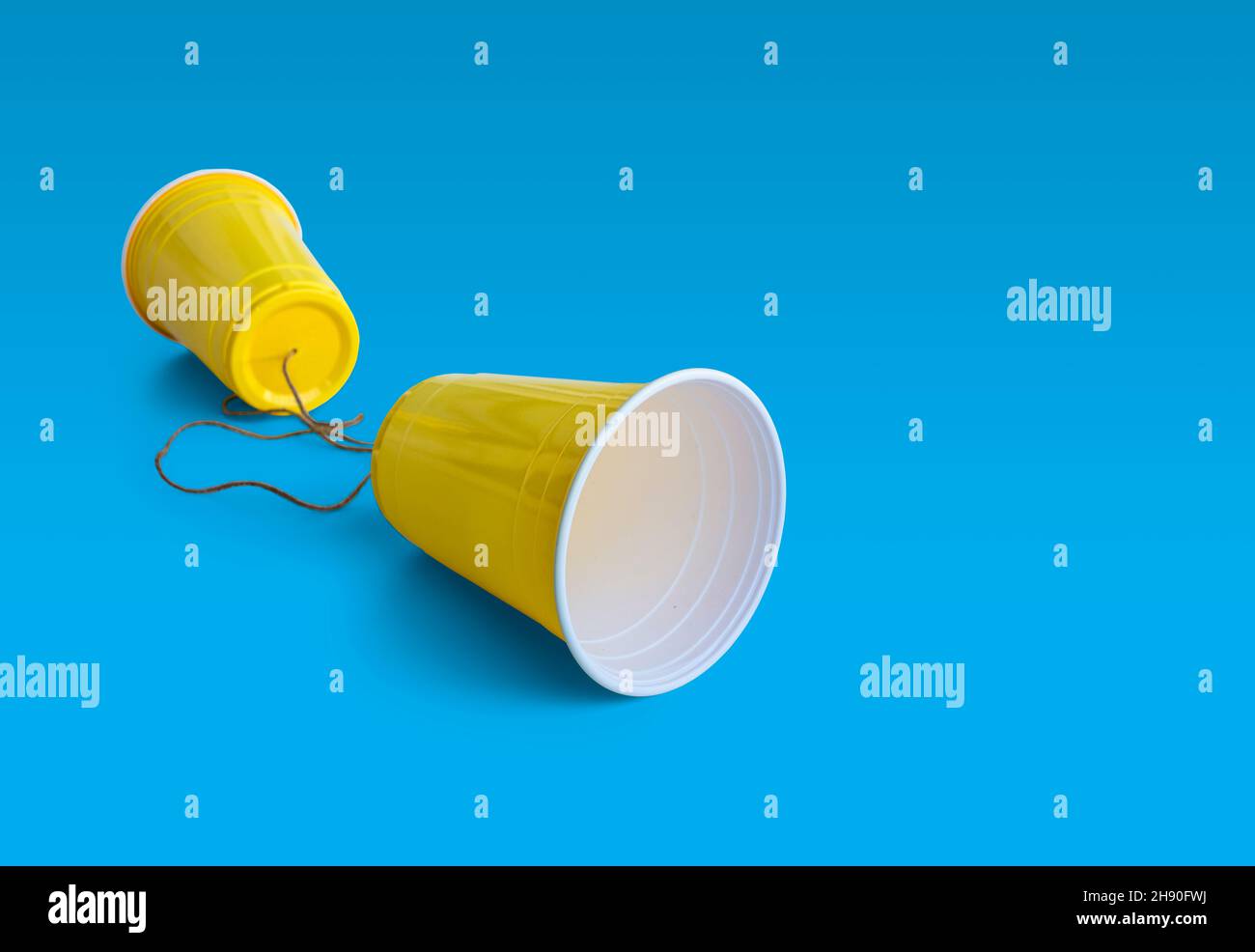 Comunication Yellow Plastic cup with string isolated on blue background Stock Photo