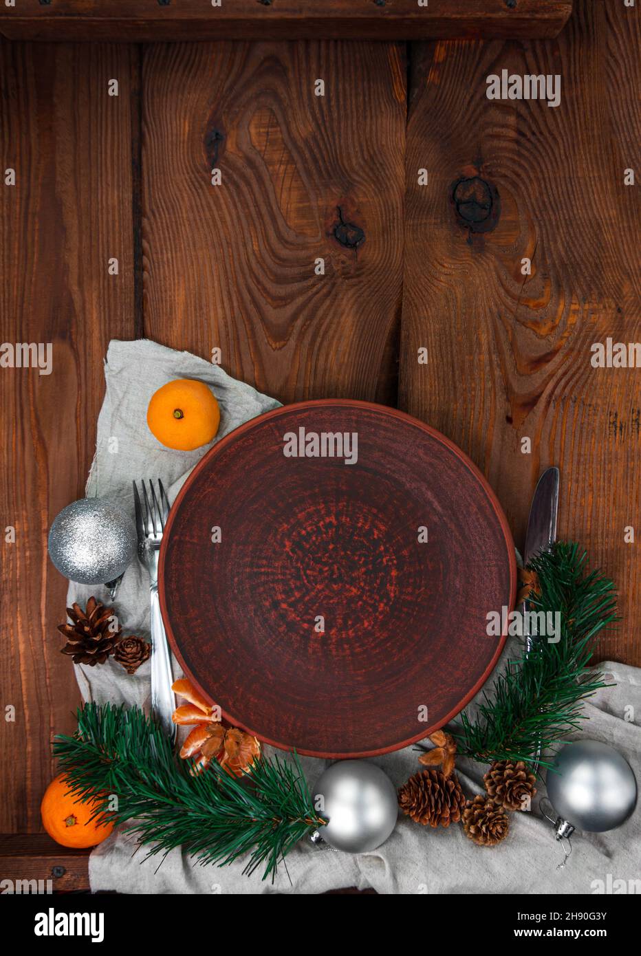 Christmas menu table setting empty clay plate fir tree tangerines festive event decoration linen tablecloth tableware Stock Photo