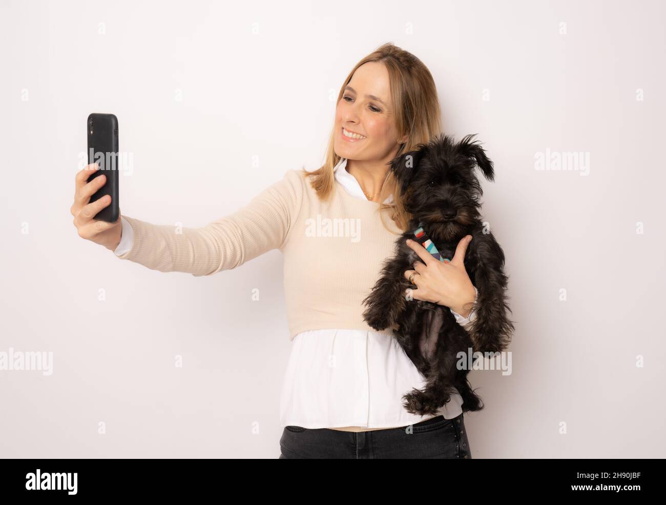Young happy woman hugging her dog making a selfie with smartphone ...