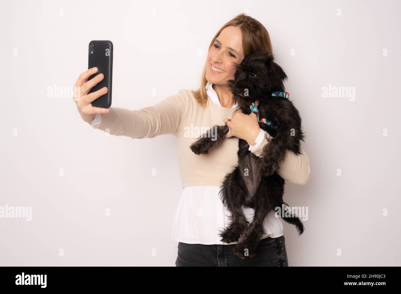 Young happy woman hugging her dog making a selfie with smartphone ...