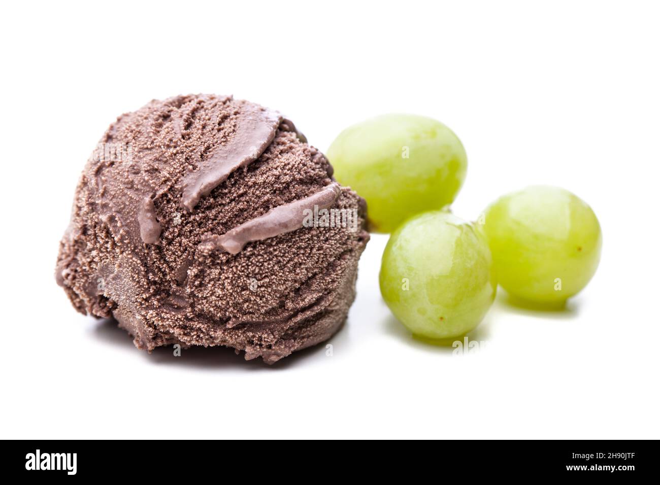 a single chocolate ice cream scoop and a few green grapes on white