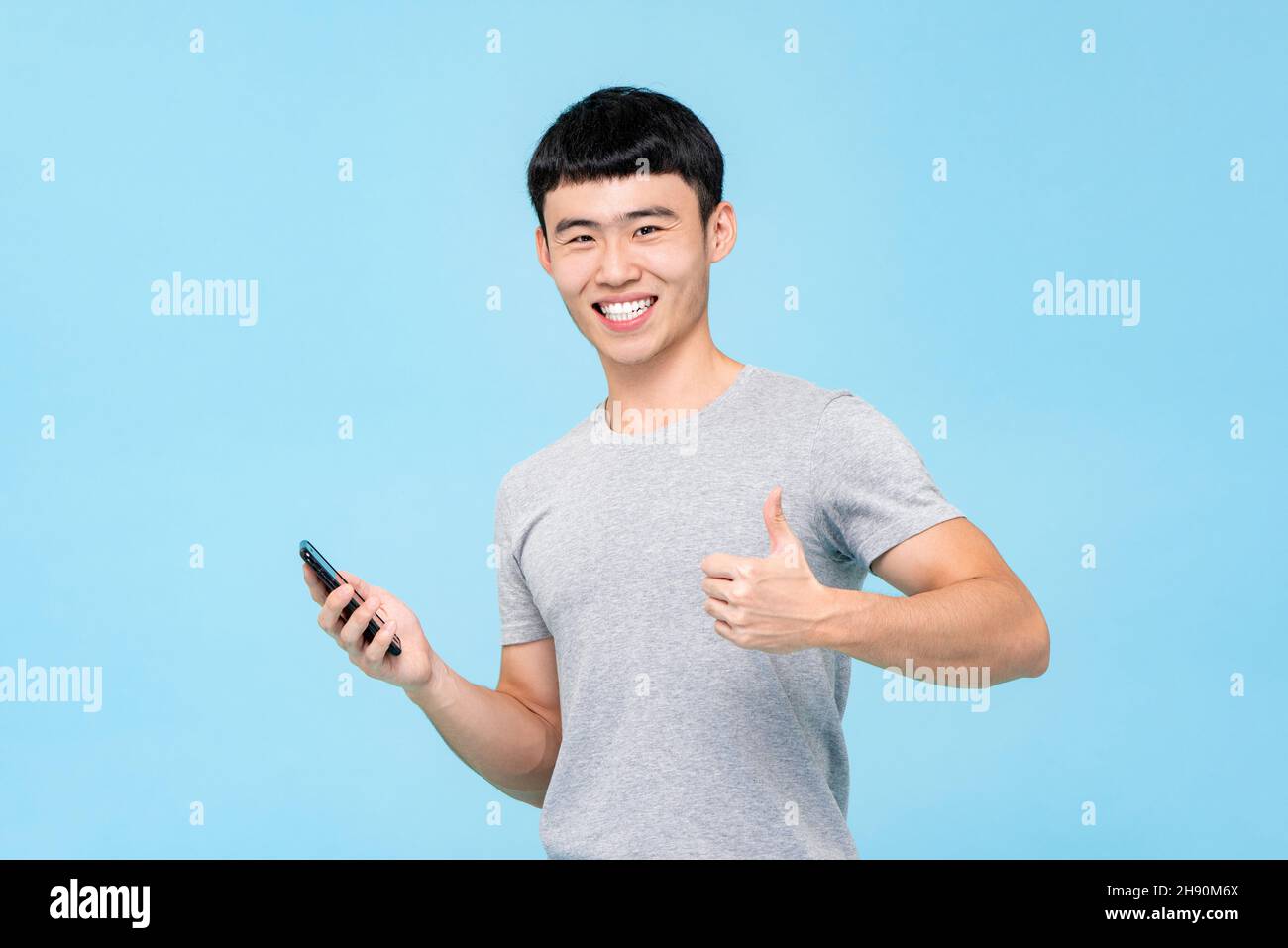 Positive happy smiling Asian man giving thumbs up while holding ...