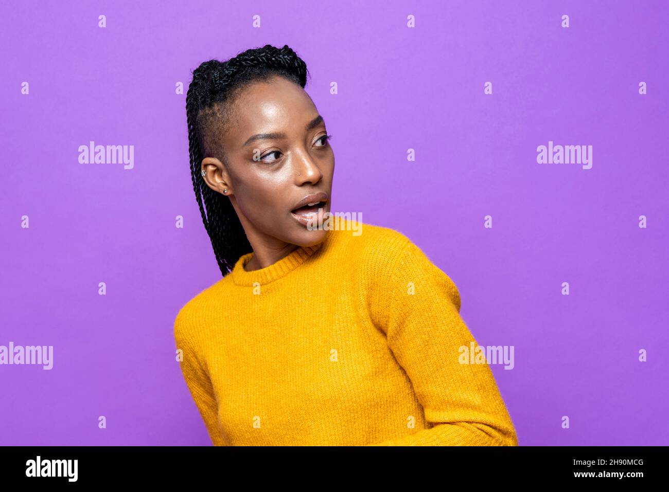 Young suspicious African-American woman looking back in isolated purple color studio background Stock Photo
