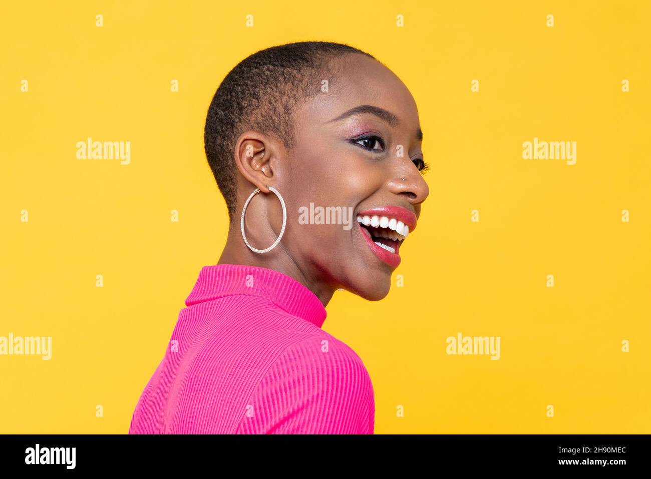 Happy smiling beautiful African American woman looking away in isolated on yellow studio background Stock Photo