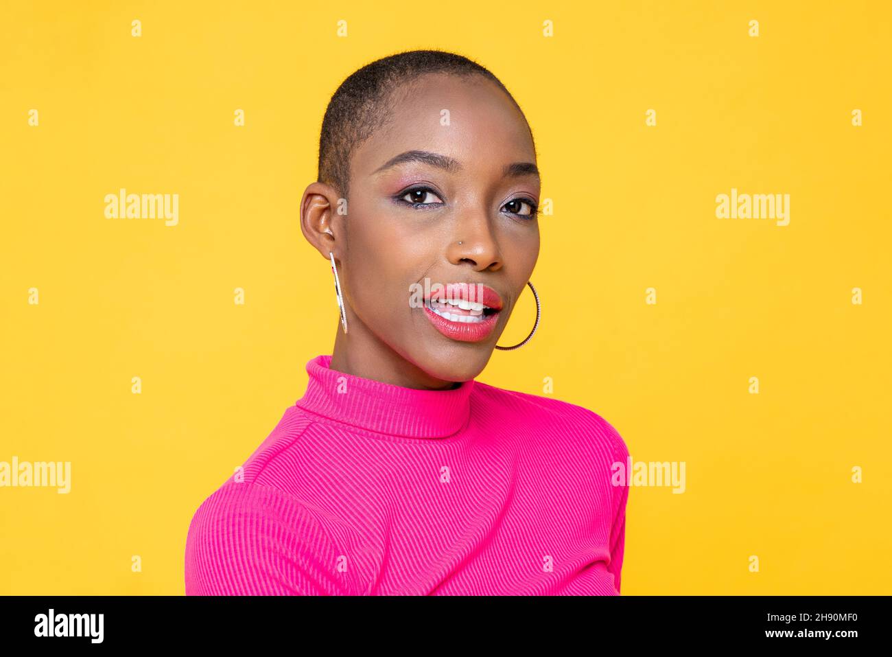Young beautiful African-American woman in shocking pink turtleneck shirt posing on yellow color isolated background Stock Photo