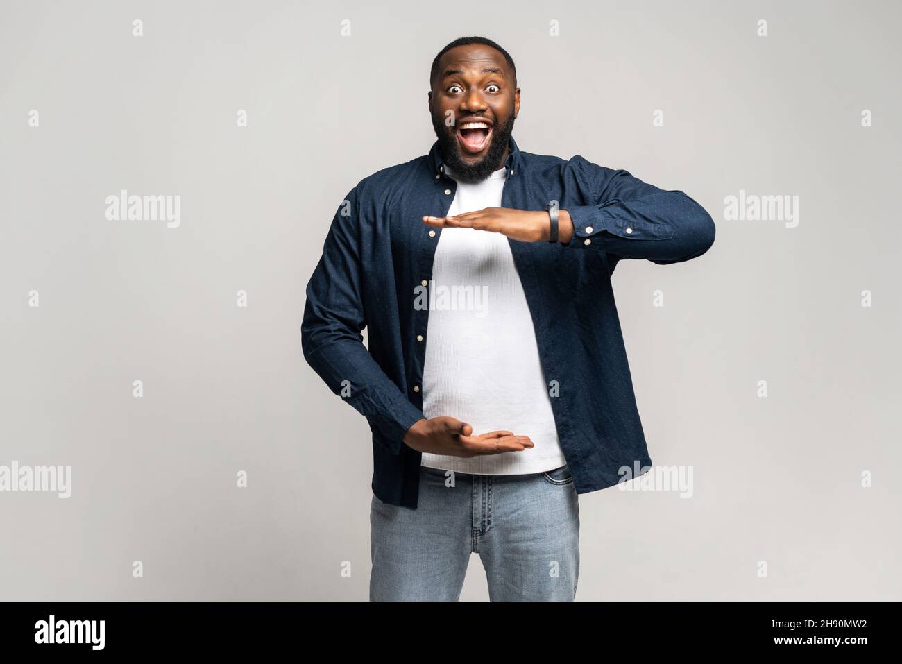 Excited surprised African man holding hands in front of him, presenting ...