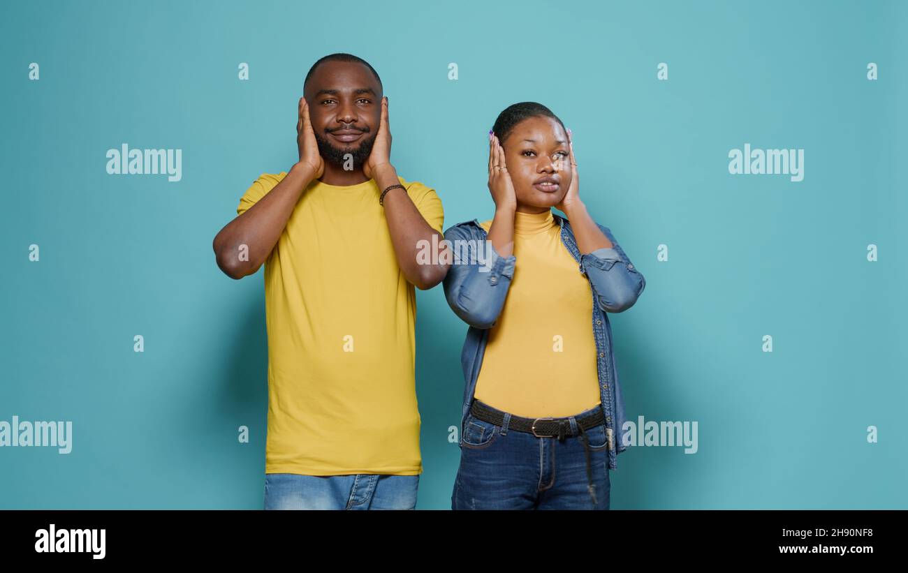Shocked man and woman covering mouth, eyes and ears in front of camera