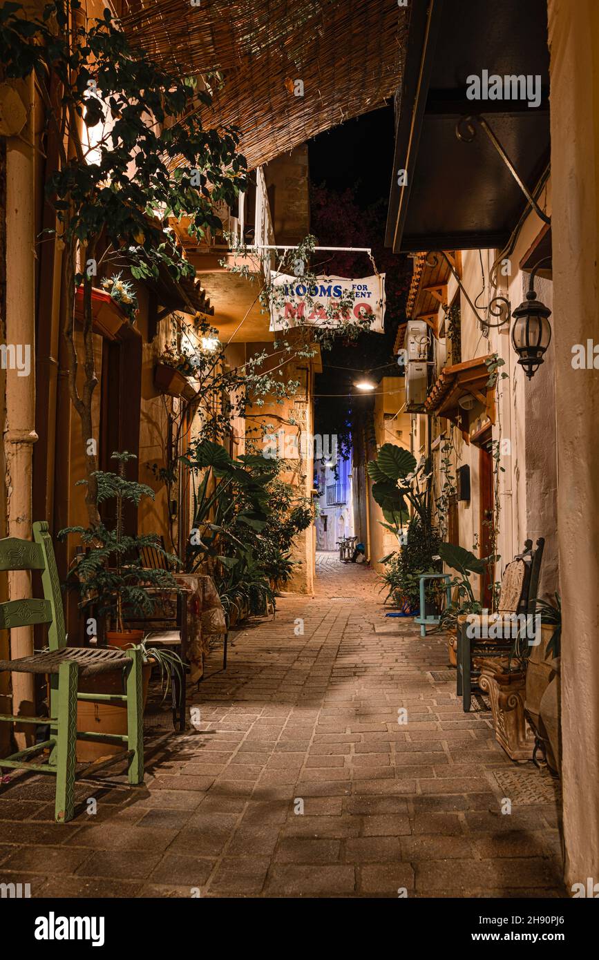 Alleyway in the old town of Chania with chairs and green plants illuminated by streetlights, Crete, Greece, October 16, 2021 Stock Photo