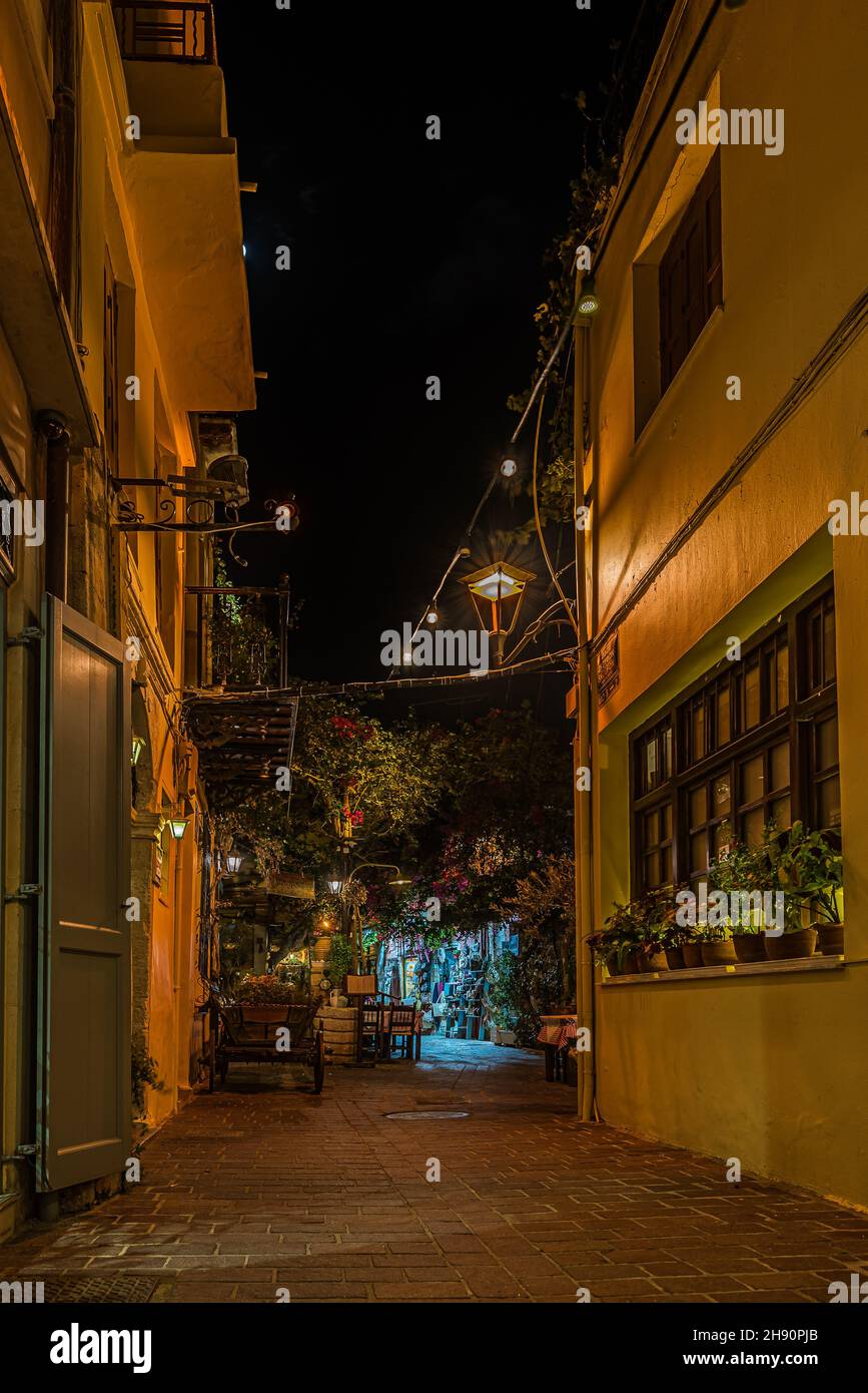 Illuminated narrow alley with gardens and restaurants in the old town of Chania, Crete, Greece, October 16, 2021 Stock Photo