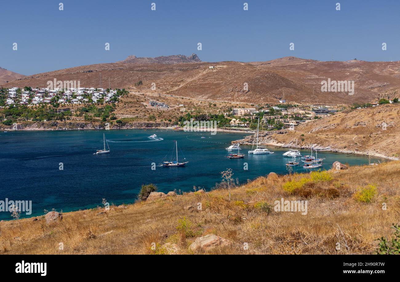 clear blue sea bay on aegean Turkish coast with moored yachts and Bodrum Imperial hotel complex Stock Photo