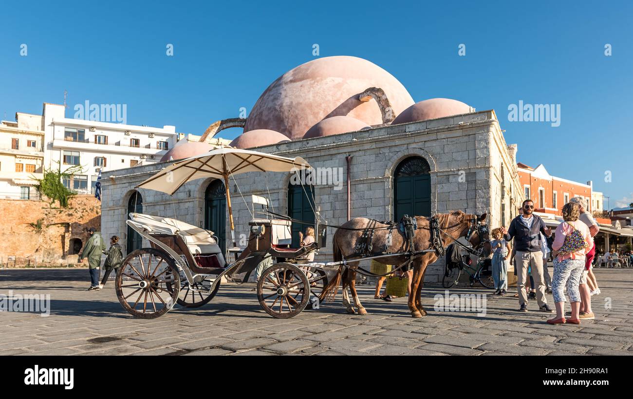 negotiating the price for a ride with a horse drawn carriage in front of the mosque in the harbour of Chania, Crete, Greece, October 16, 2021 Stock Photo