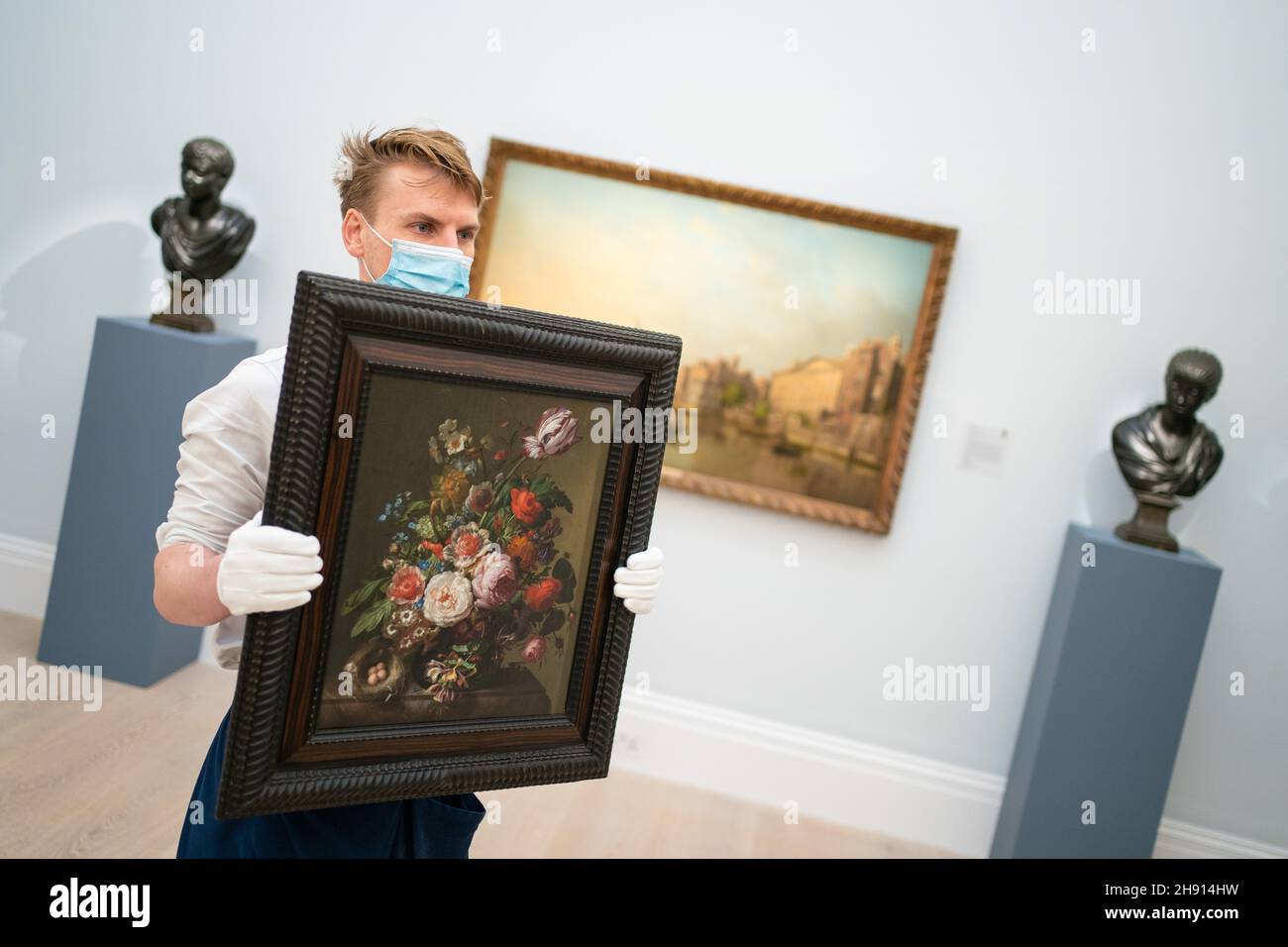 A Sotheby's art handler holds 'Still life of flowers in a vase with a bird's nest upon a mable edge' by Rachel Ruysch, valued at £1,200,000 to £1,800,000, during a photo call at Sotheby's in Mayfair, London, for their forthcoming flagship Old Masters Evening Sale which includes a rediscovered study by John Constable, a rarely seen pair of portraits by Sir Anthony Van Dyck and a recently rediscovered oil painting by JMW Turner. Picture date: Friday December 3, 2021. Stock Photo
