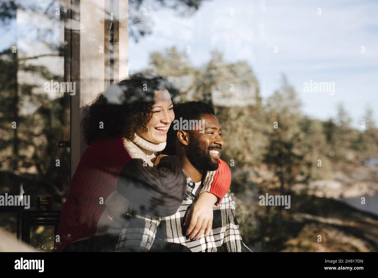 Smiling couple looking away seen through window Stock Photo