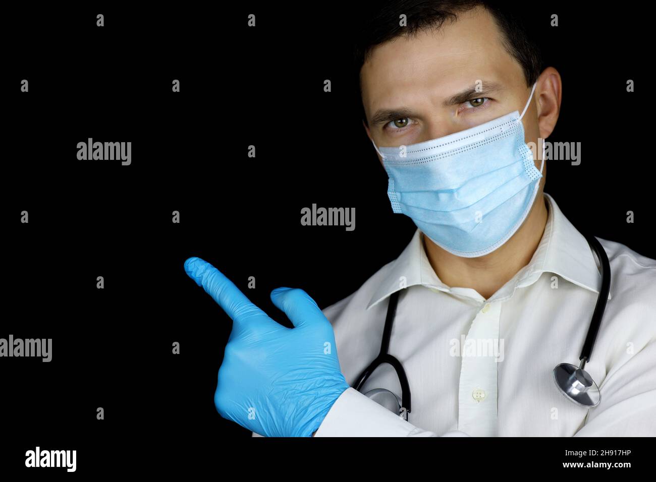 Doctor in disposable face and medical gloves mask points up with his finger. Concept of call for participation, health care, coronavirus protection Stock Photo