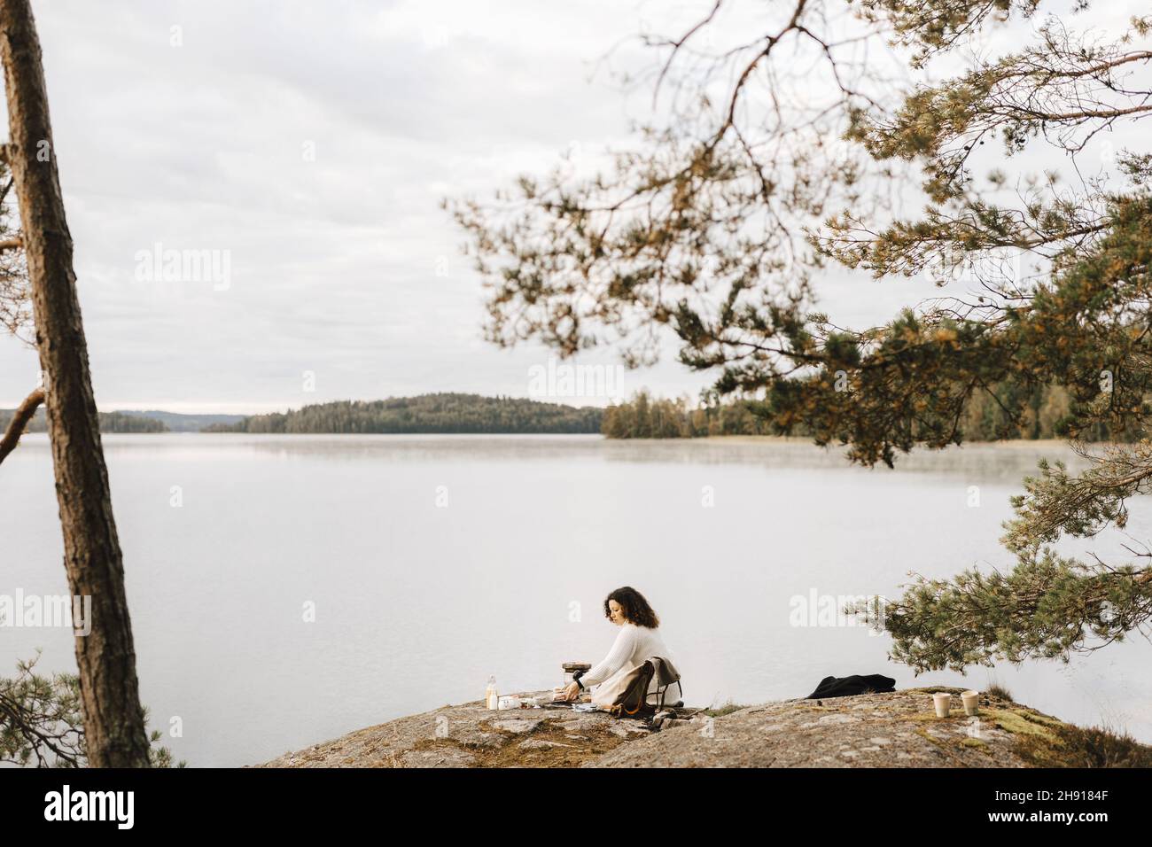 Young woman sitting on rock at lakeshore Stock Photo