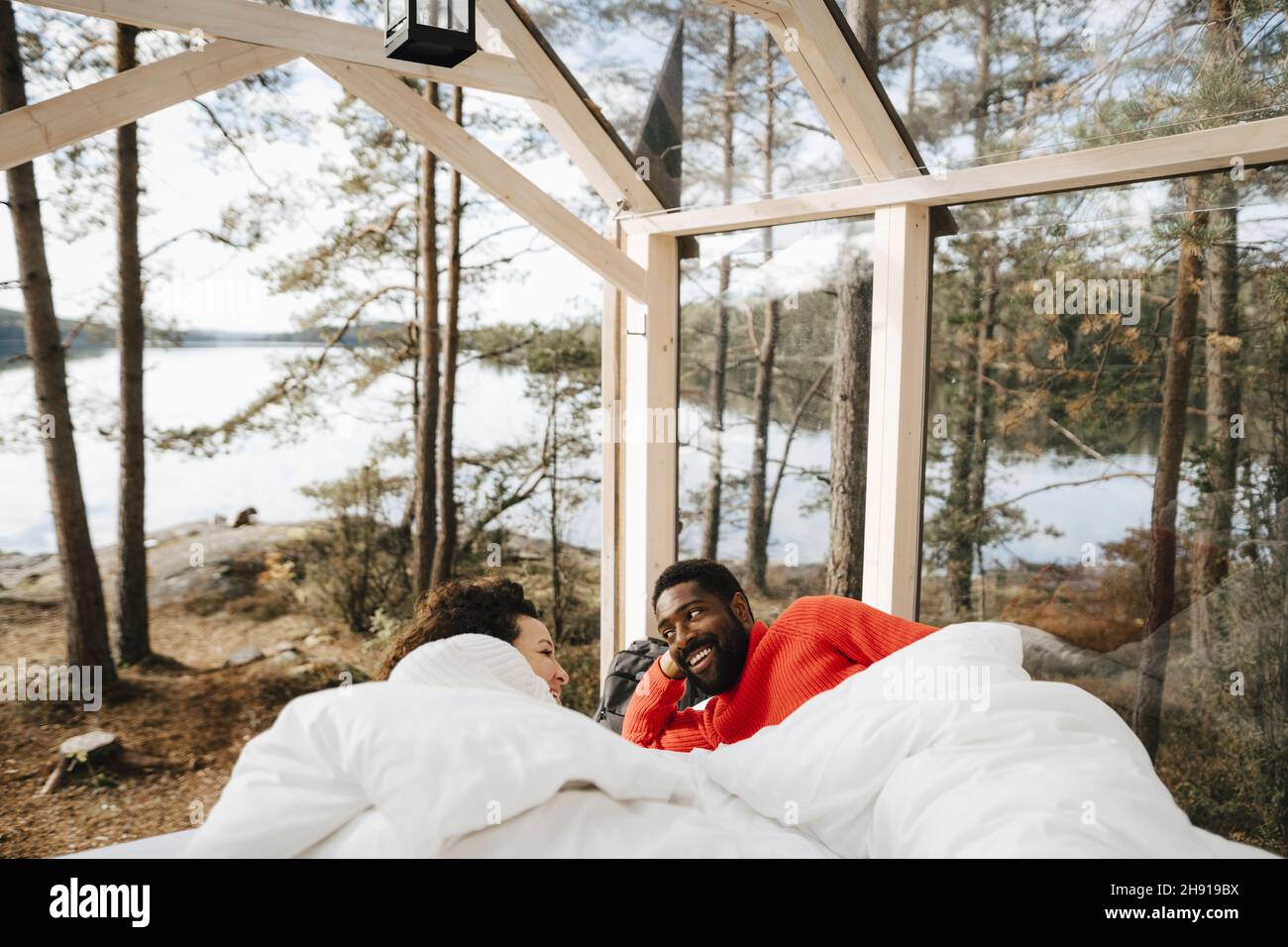 Happy couple talking while lying in cottage during weekend Stock Photo