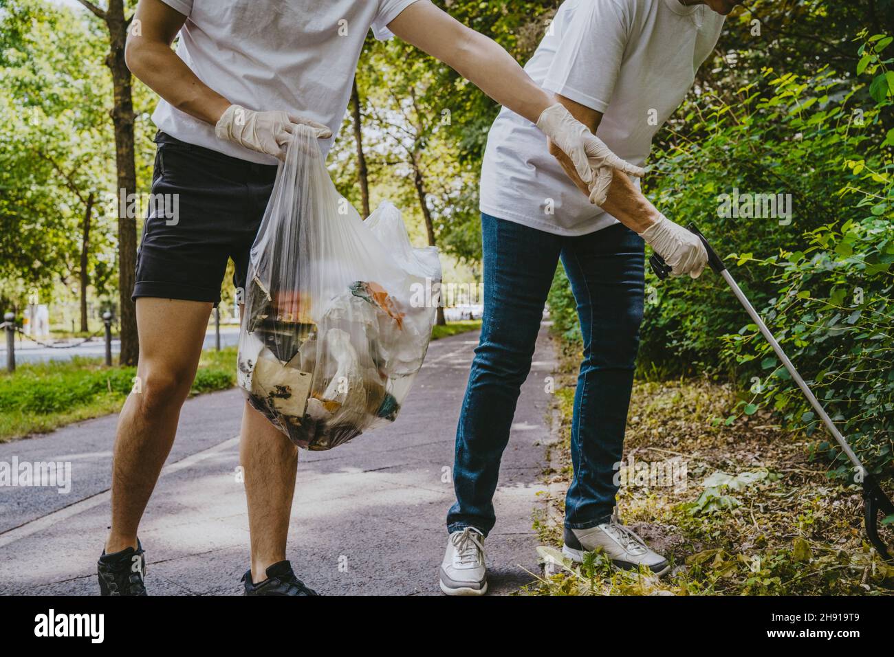 Low section of male and female volunteers picking up plastic at park Stock Photo