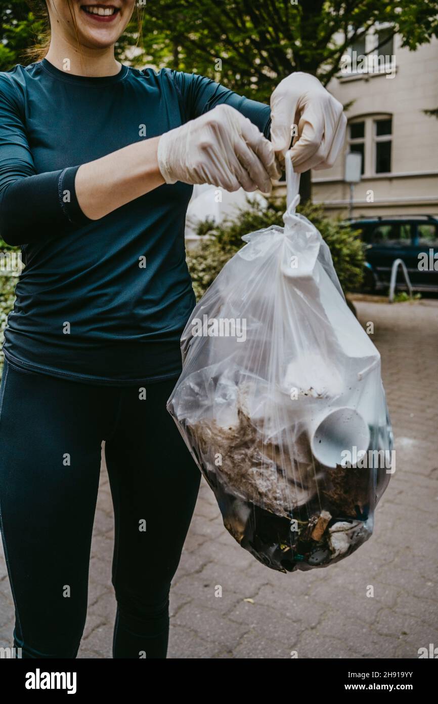 Midsection of female volunteer holding plastic bag Stock Photo