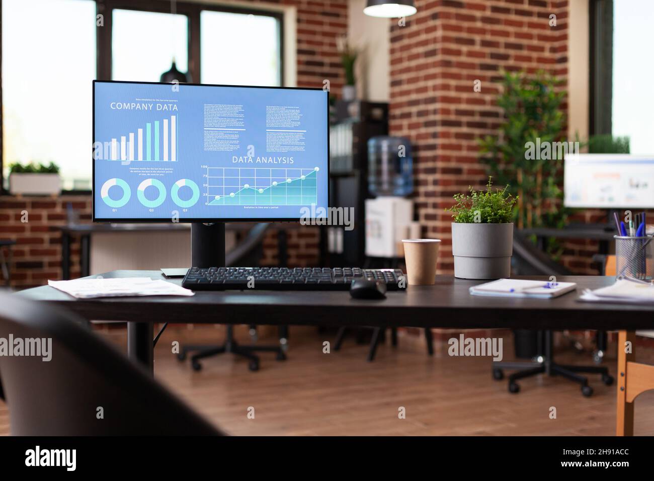 Close up of computer with company data analysis on desk in empty office.  Monitor with business diagram and analytics on display to follow database  growth. Nobody in startup space Stock Photo -