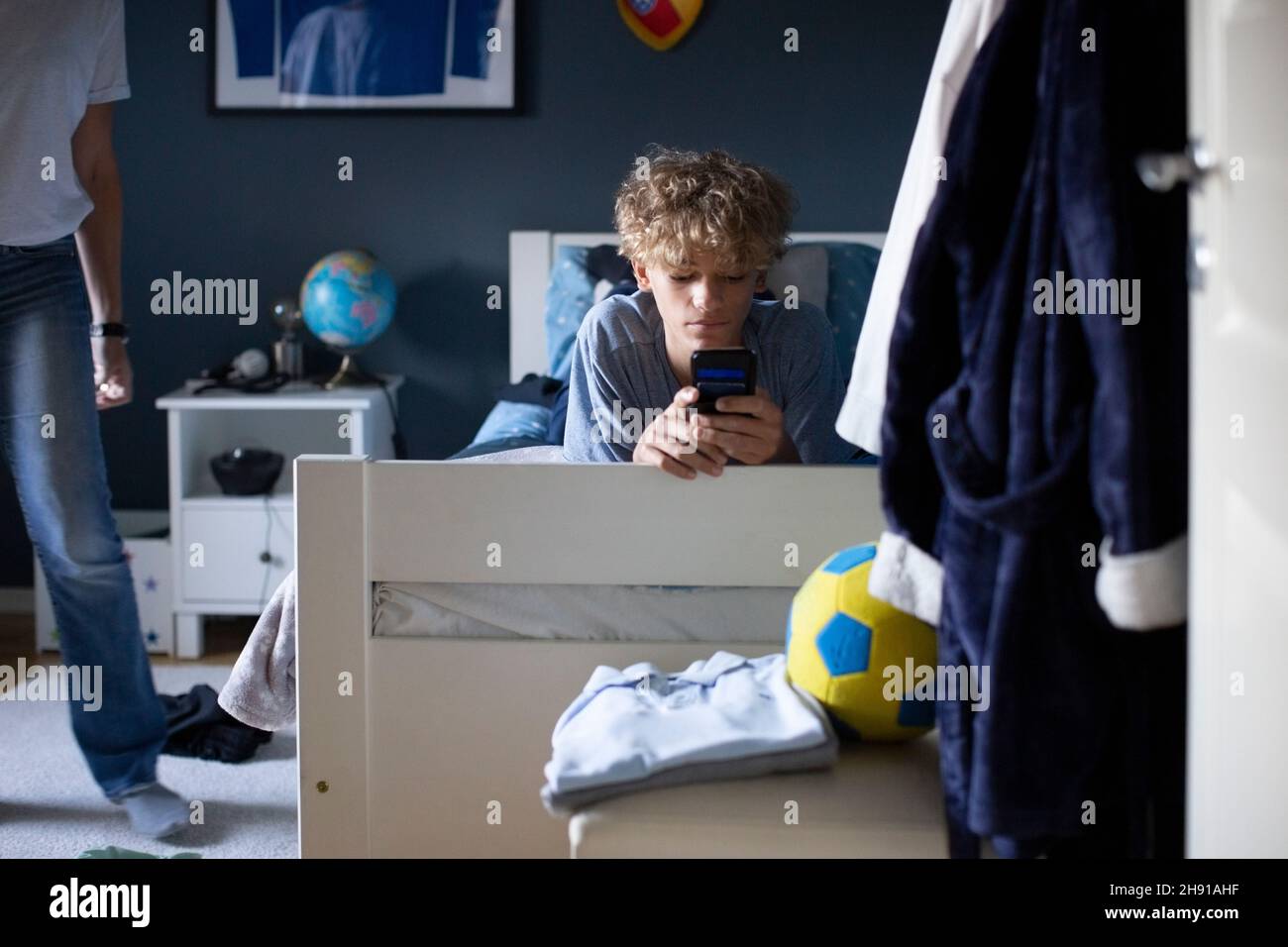 Boy using mobile phone while lying on bed at home Stock Photo