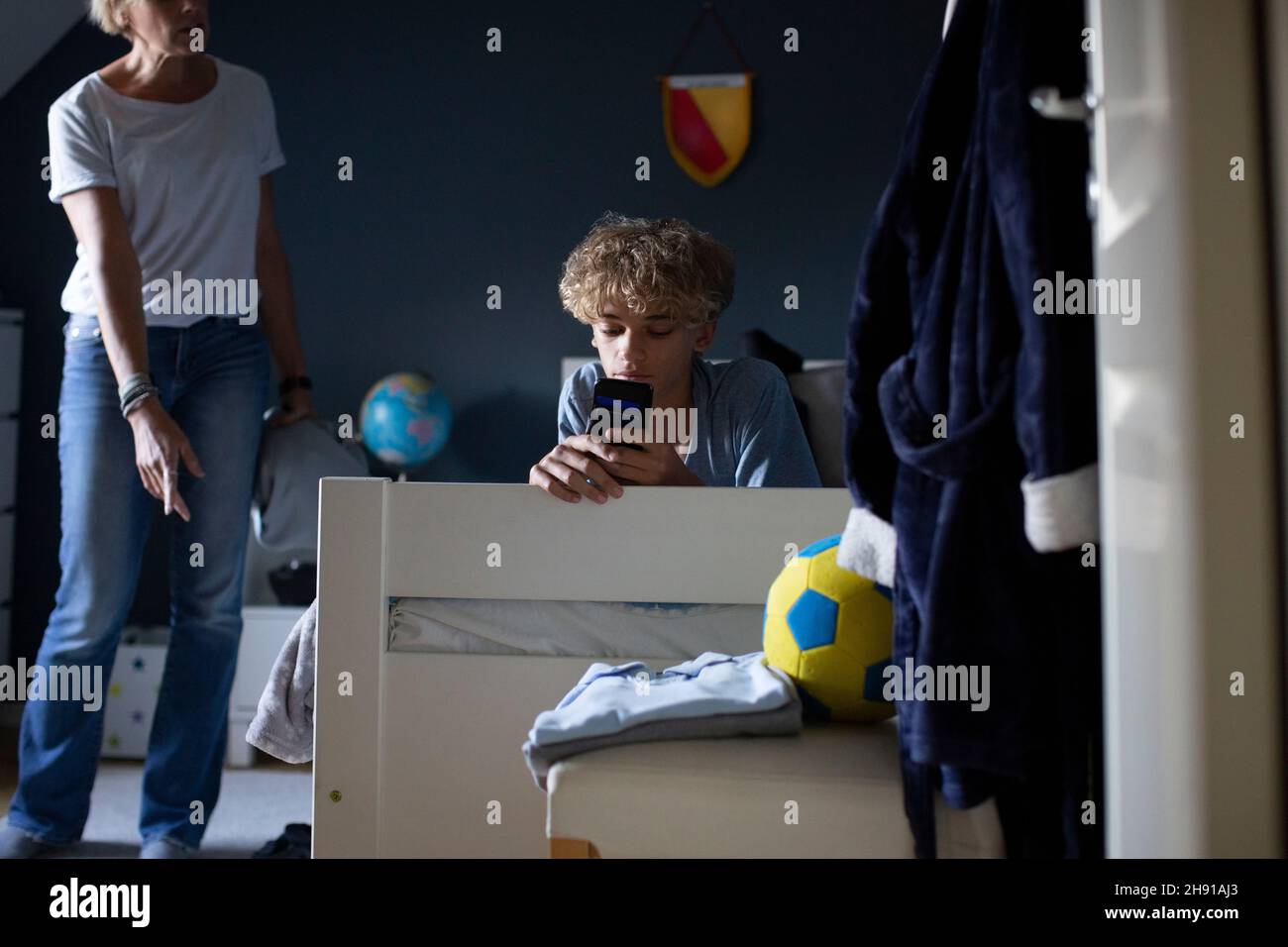 Mother scolding son using smart phone while lying on bed at home Stock Photo