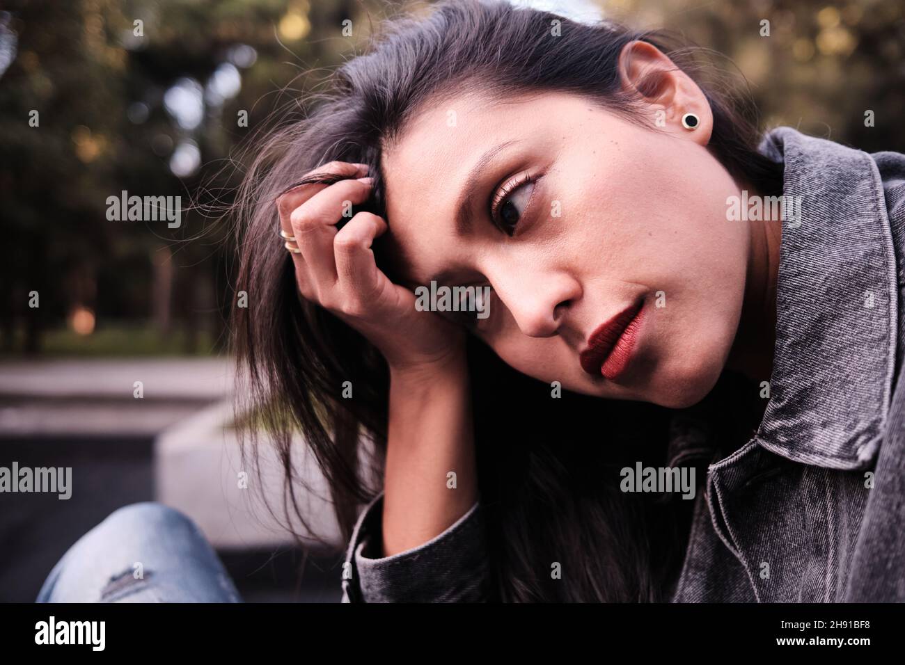 A preoccupied gilrl holding her head in her hand. Stock Photo