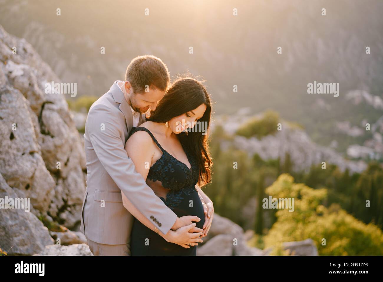 Man hugs a pregnant woman on top of a rocky mountain Stock Photo - Alamy
