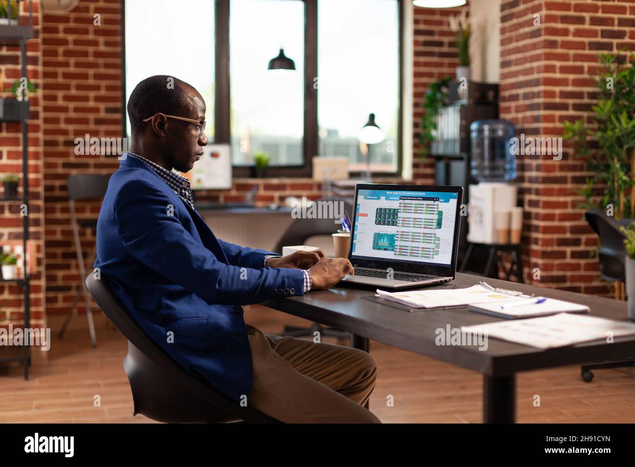 Business man looking at data chart to do stock market analysis for company growth on laptop. Entrepreneur looking at global money trade to invest in crypto currency and work on project. Stock Photo