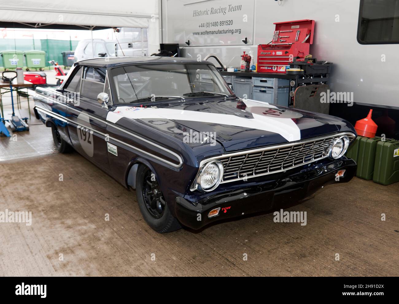 Three-quarters front view of a Dark Blue, 1964 Ford Falcon, in the pit garage of the Historic Racing Team, at the 2021 Silverstone Classic Stock Photo