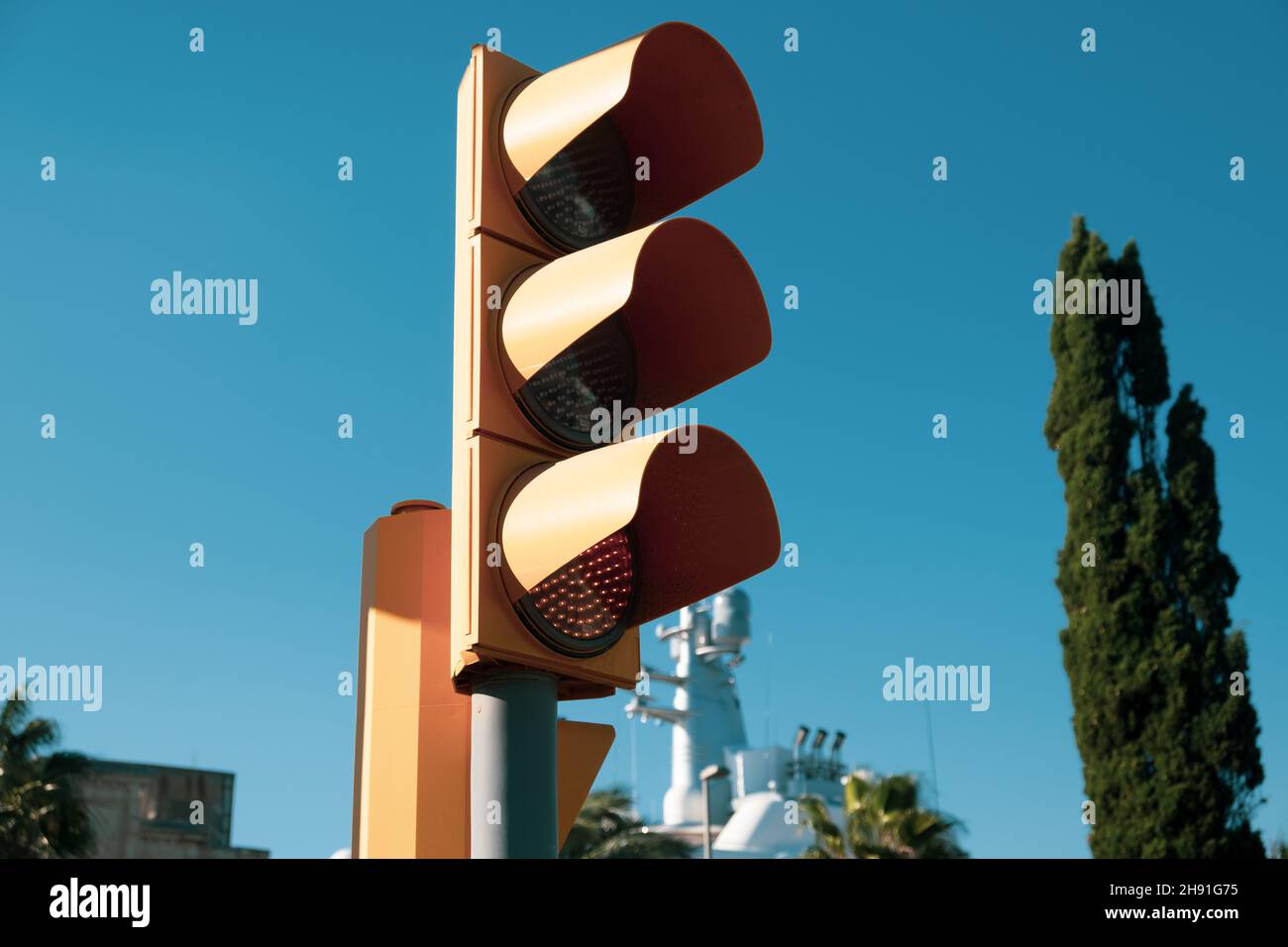 Traffic light with yellow light closeup on blue blurry sky background