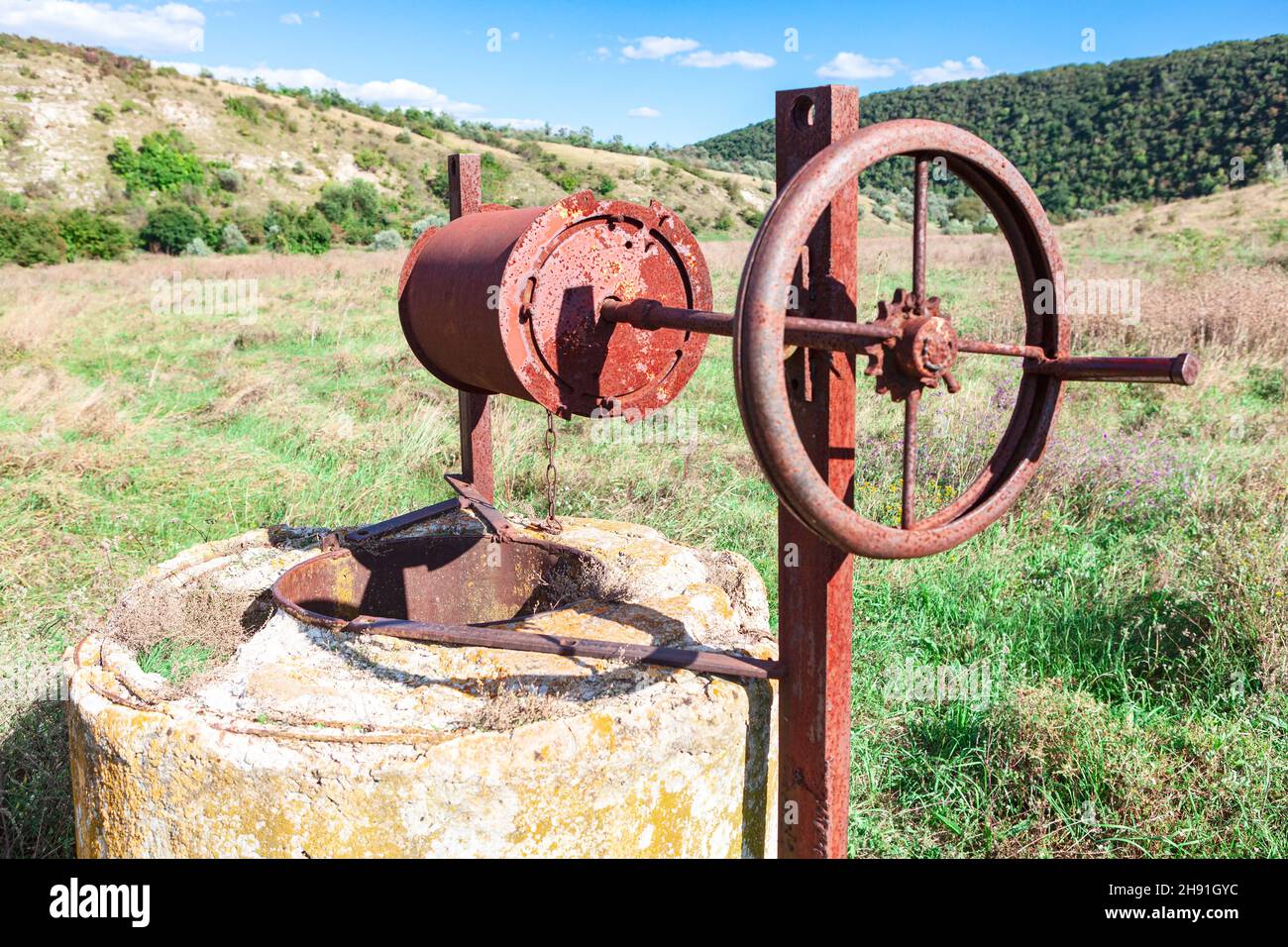 Well with rust mechanism . Old abandoned water well Stock Photo - Alamy