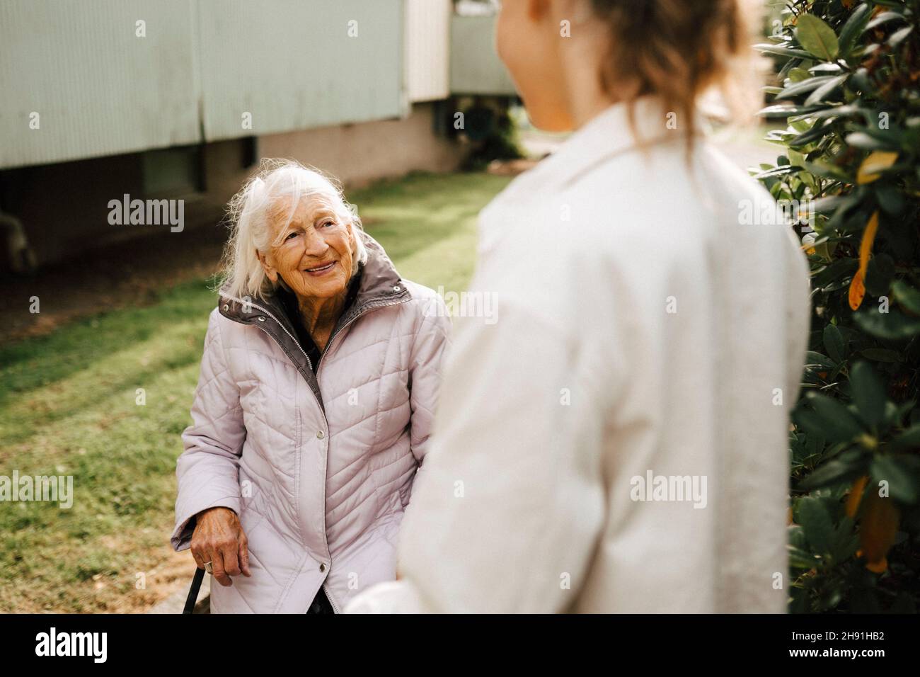 Smiling elder woman talking with female caregiver in front yard Stock Photo